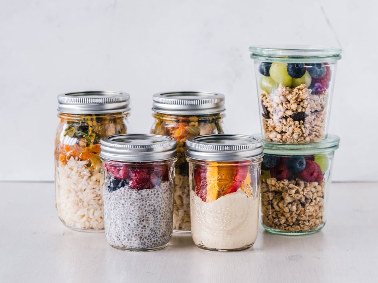 Close-up of healthy food jars containing granola, fruits, and yogurt.